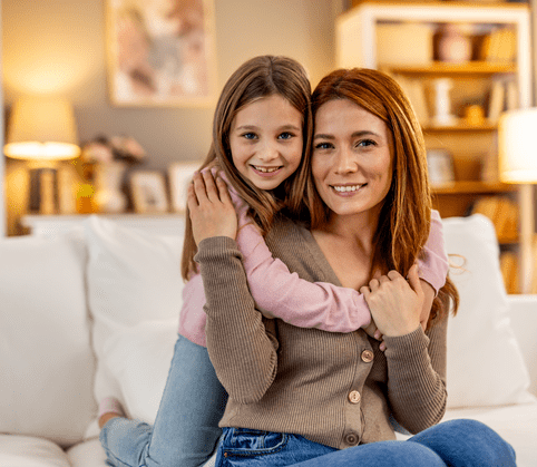 A cheerful and loving moment between a mother and daughter embracing each other warmly in a cozy living room setting, showcasing family connection, love, and togetherness.