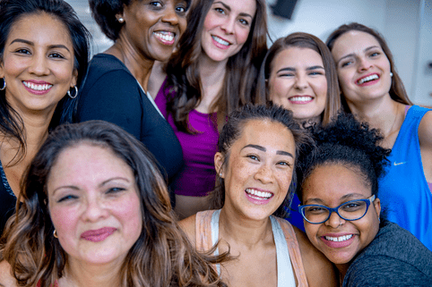 Leading-edge treatments for breast cancer, precisely matched to you A multi-ethnic group of adult women are posing for a group photo together. They are in a health center, and they are wearing sports clothing.