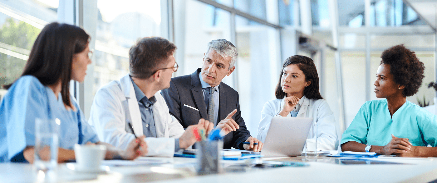 Group of medical experts having a business meeting with businessman in a hospital.