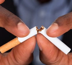 African American Man breaking a cigarette in half
