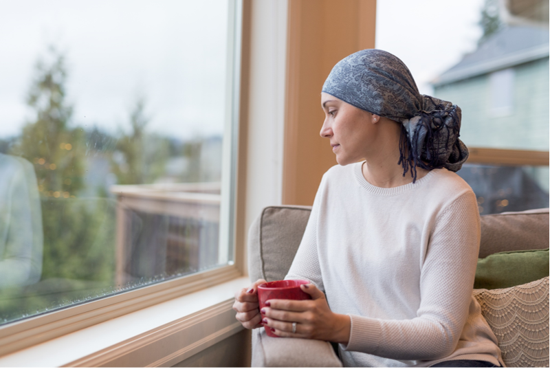 Woman cancer survivor sitting in a chair with a cup of coffee
