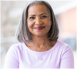 Woman in pink smiles at viewer