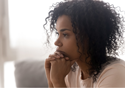Black Woman sitting on a couch staring in the distance