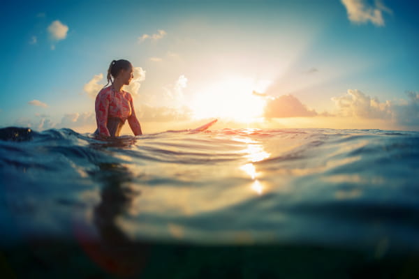Woman sitting on surfboard in water