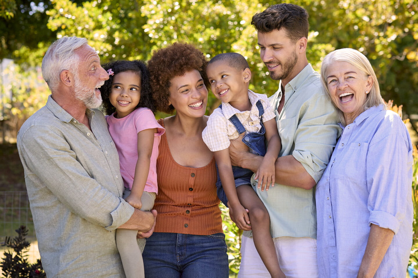 Portrait Of Multi-Generation Family Standing In Garden Smiling At Camera