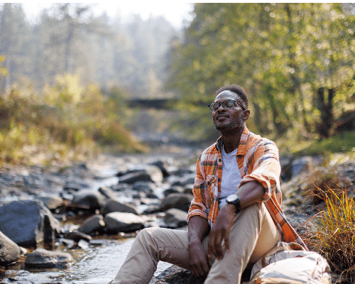 Man resting by a river in the forest 