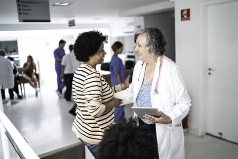 Female senior doctor welcoming / greeting mother and daughter at hospital