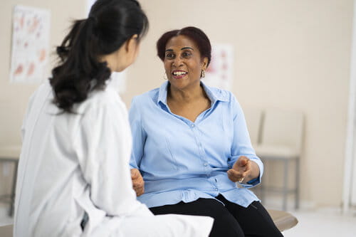 A senior citizen of african descent listens to her doctor explain the outcome of her most recent tests.