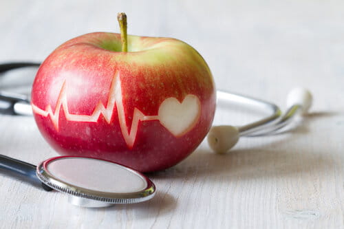 Heartbeat line on red apple and stethoscope, healthy heart diet concept background