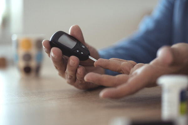 Man measuring glucose test level check with blood on finger by glucometer she monitor and control high blood sugar diabetes and glycemic health care