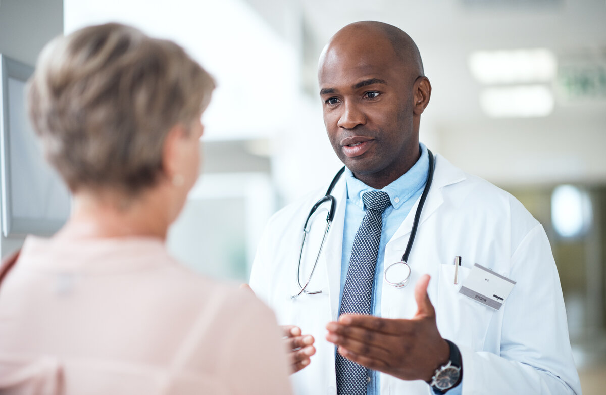 Cropped shot of a handsome mature male doctor talking to a female patient in the hospital corridor