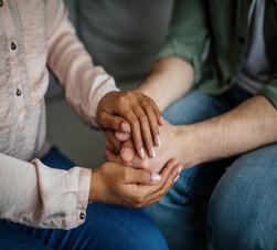 Cropped young african american woman doctor holding hands with patient supporting client at meeting in office clinic interior, close up. Psychological therapy, session with professional, mental help