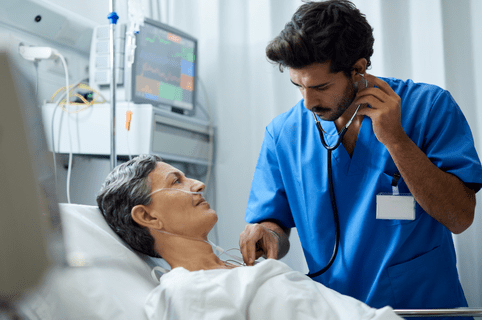 A male nurse is listening with a stethoscope a patient's chest