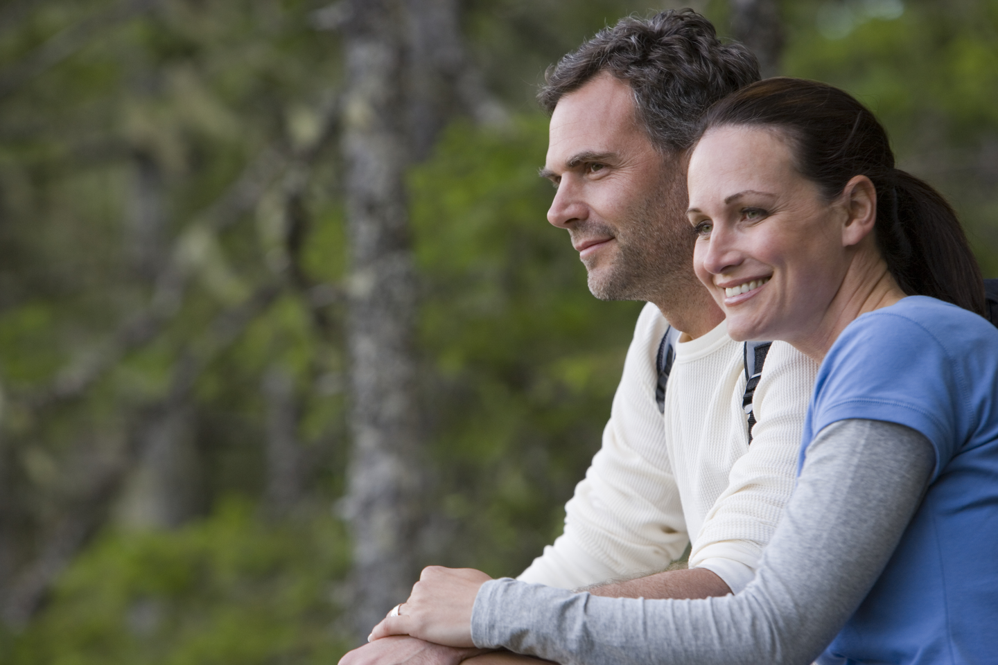 Couple in forest, looking at view and smiling