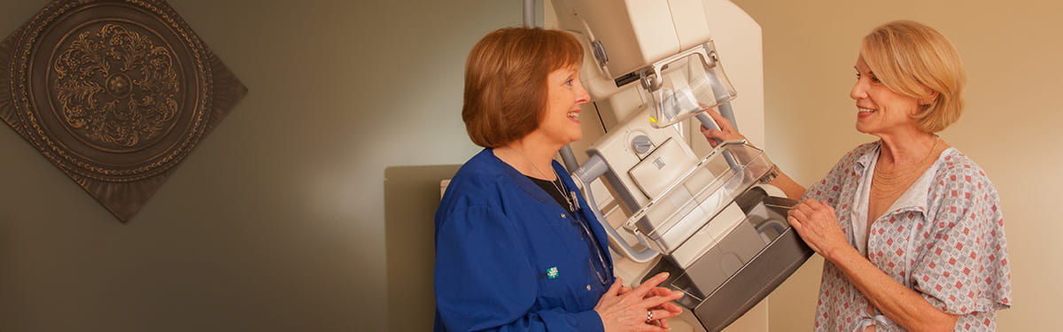 Radiologist speaking with smiling patient in front of an imaging machine