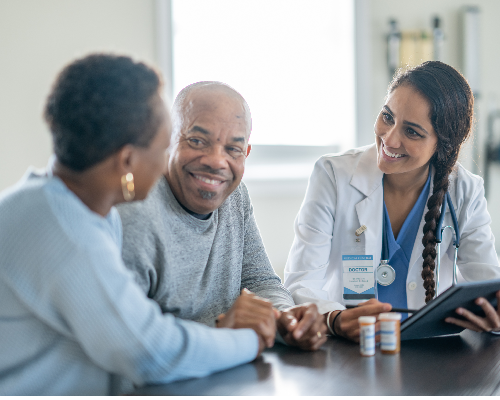 Healthcare provider consulting with patient and companion in clinic, discussing care plan at table