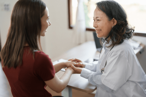 Female doctor holding the hands of a  female patient