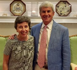 Man and woman standing together smiling in front of a white fireplace