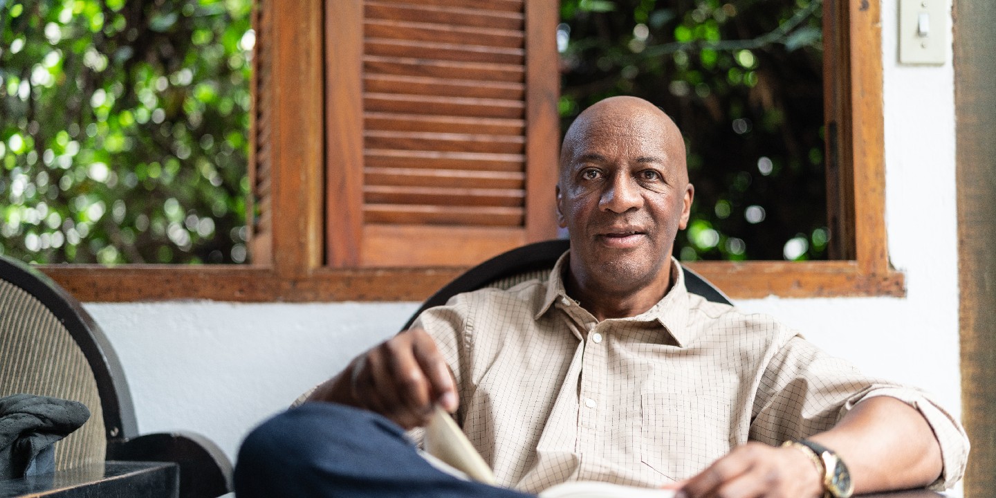 Memory Care Program Neuro Spine Diagnosis Afro Mature Man Reading a Book at Home