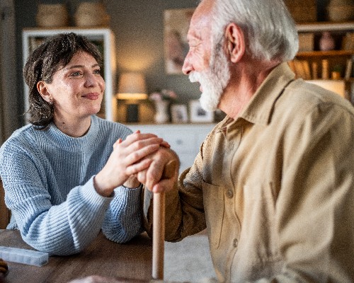 Young woman holding hands of senior man with walking stick Neuro Spine Memory Care Goodson Center