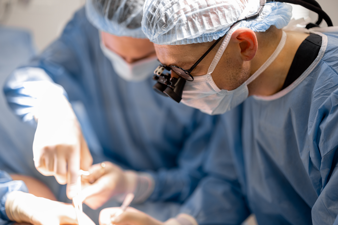 Three confident surgeons performing surgical operation on a patient's knee in operating room. Concept of real surgery and invasive treatments
