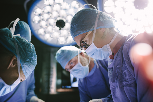 Concentrated female surgeon performing surgery with her team in hospital operating room. Medics during surgery in operation theater.