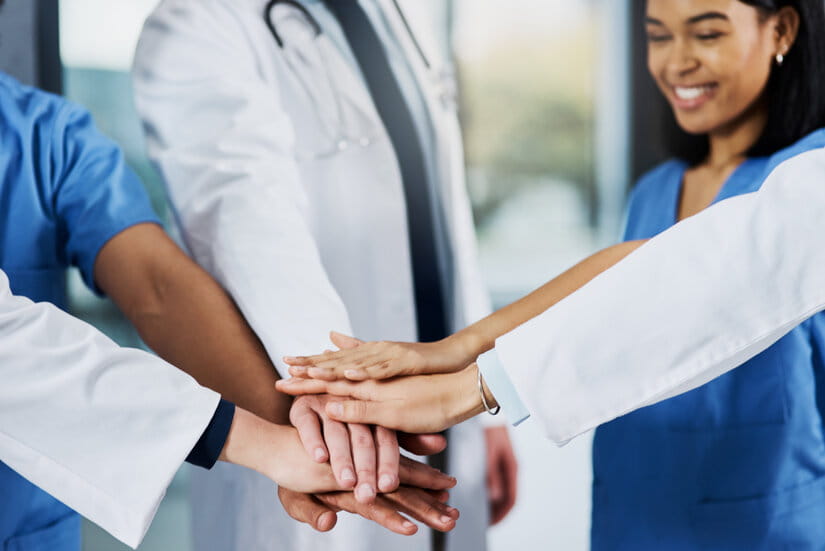Closeup shot of a group of medical practitioners joining their hands together in a huddle
