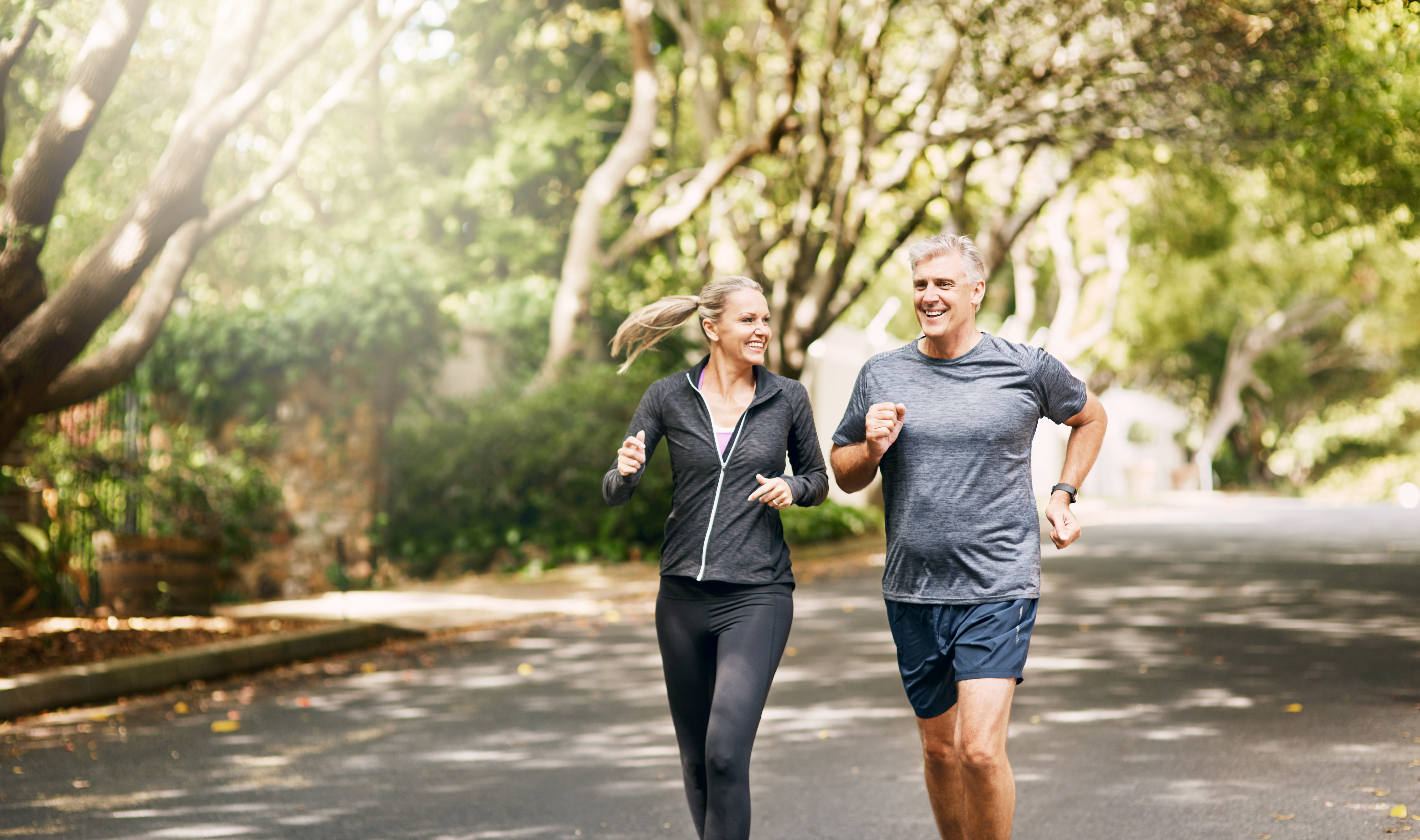 Active couple jogging outdoors, promoting orthopedic and sports medicine care for joint health, injury prevention, and overall mobility.