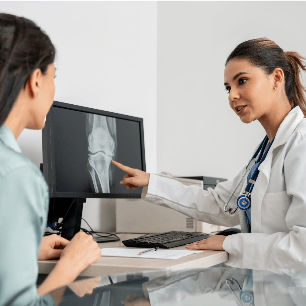 OrthoConnect Doctor in her office looking at a knee x-ray with a patient using a computer