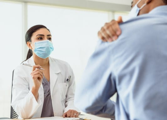 Patient indicates to healthcare worker that his shoulder hurts