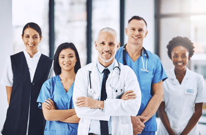 Cropped portrait of a handsome mature male doctor standing with his arms folded with his team behind him
