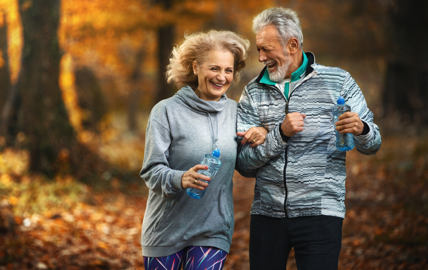 Closeup side view of a mature couple jogging in a forest on a November day as a part of their weekend routine.