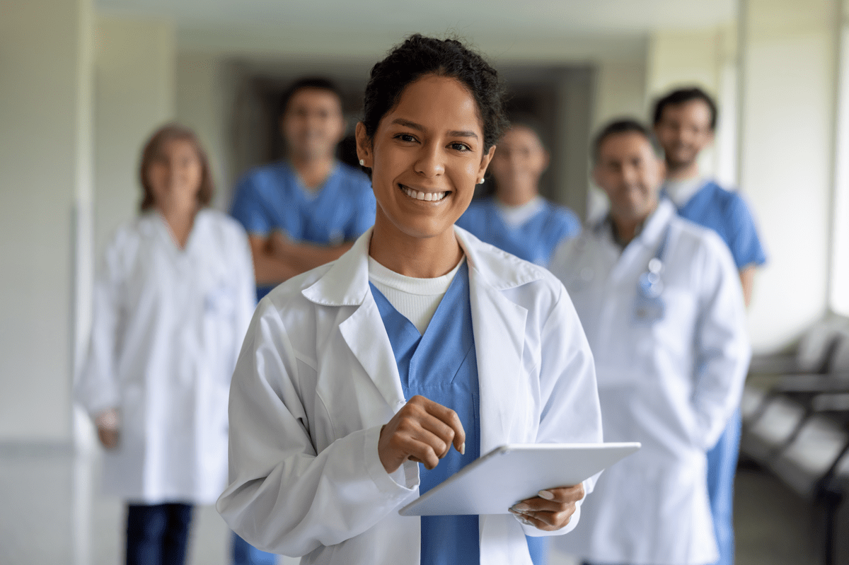 Happy female doctor leading a team of healthcare workers at the hospital and looking at the camera smiling