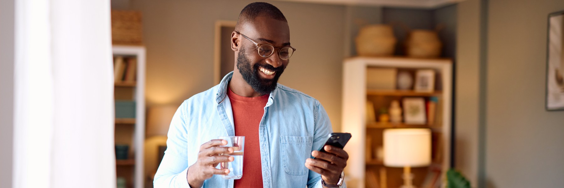 Primary Care Heredity Risk personalize approach Smiling man drinking water and using smartphone at home