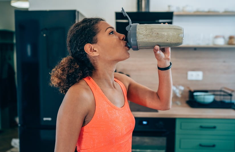 Primary Care Young woman drinking protein shake after workout at home. 