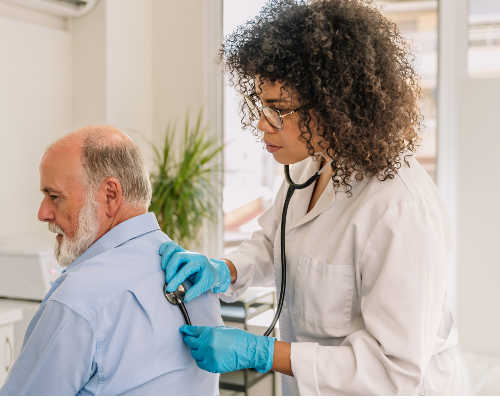 Female doctor examining his senior male patient using stethoscop