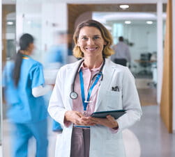 Critical Care Team icon Portrait Of Female Doctor In White Coat And Digital Tablet In Hospital With Colleagues In Background