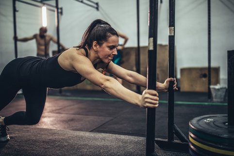 Strong young woman pushing heavy weights at the gym