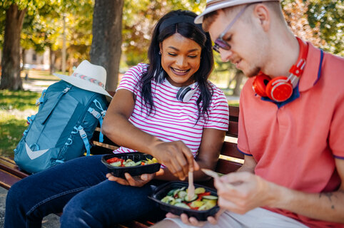 Two young adults with backpacks in park