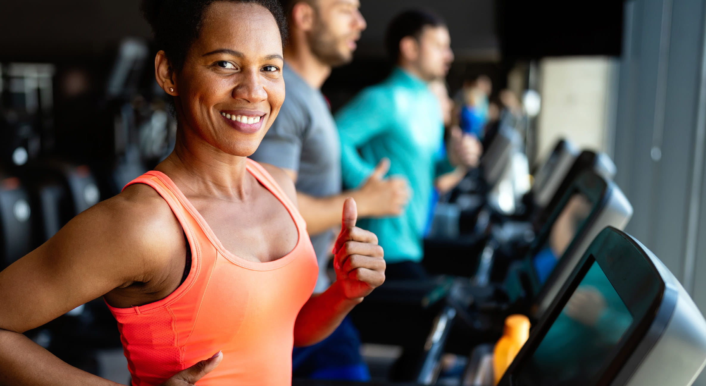 African American Woman in an orange shirt running on a treadmill