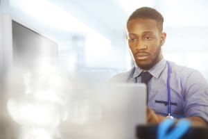 black physician looking at a computer