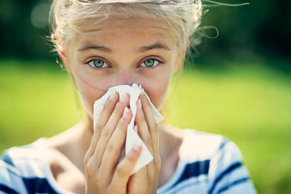 Portrait of teenage girl blowing her nose on a summer day