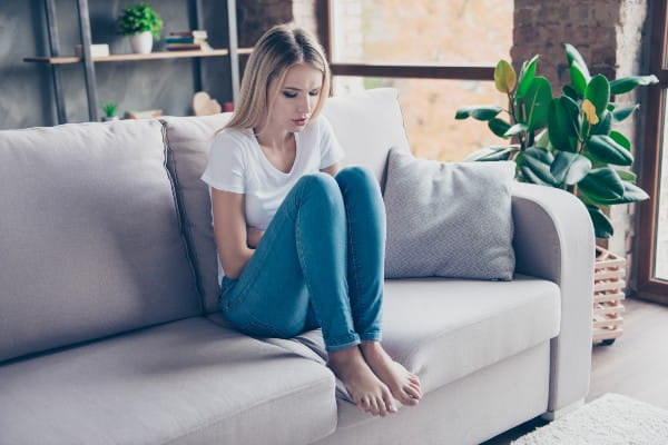 Woman sitting on a sofa and touching her stomach