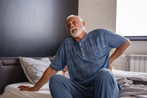 A senior man has low back pain