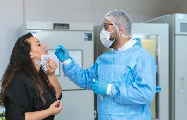 Male doctor in protective suits taking swab test from a female patient in hospital