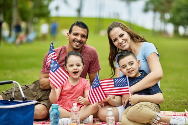 Family sitting in a park holding American Flags