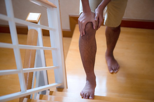 Man suffering from knee pain while stepping up the stairs