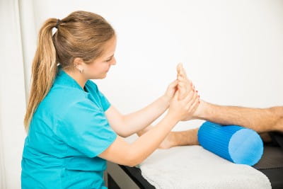 Female physiotherapy professional massaging patient's foot