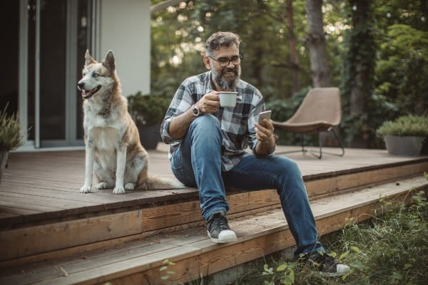 Mature men at his cottage resting on porch with his dog.