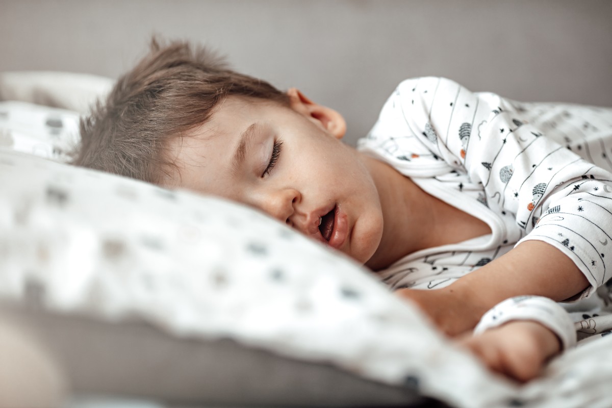 Little blond boy sleeping in his bed